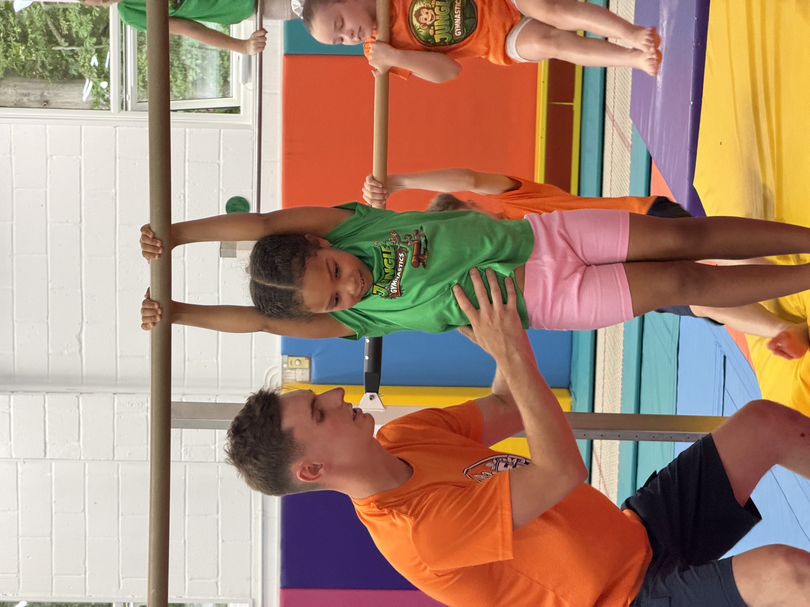 A gymnast working on the high bar with a coach